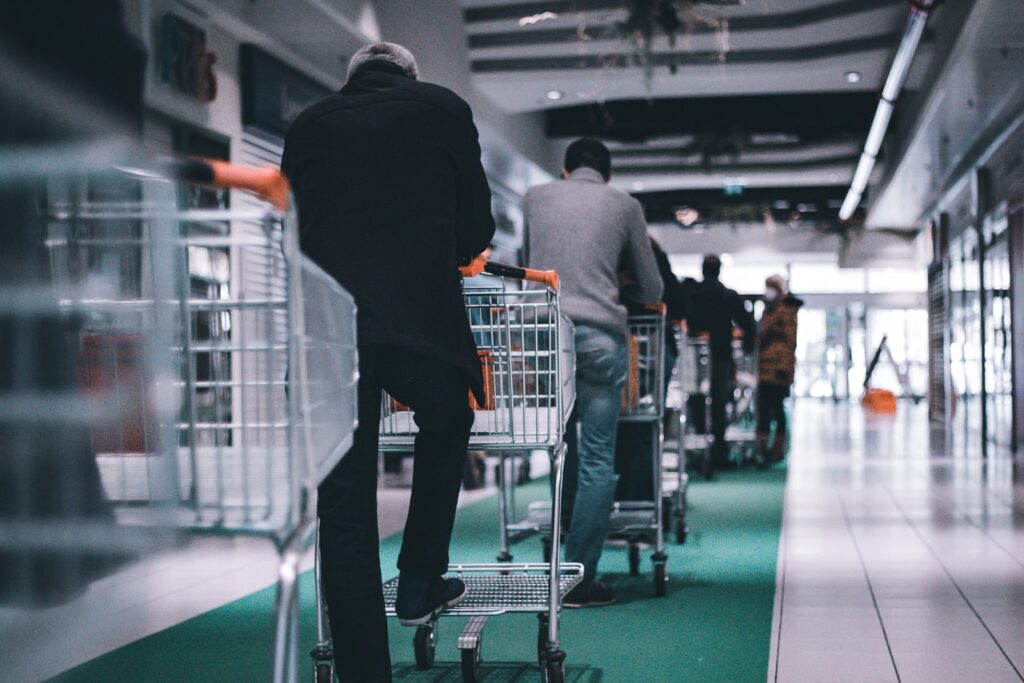 man in black long sleeve shirt and black pants standing on shopping cart